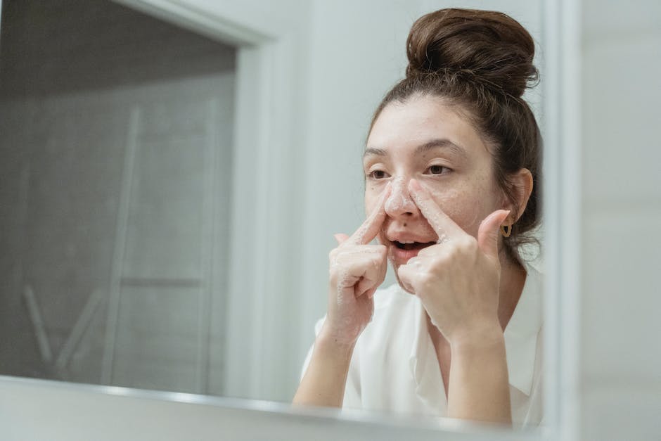 A young woman applies skincare in front of a bathroom mirror, focusing on facial care