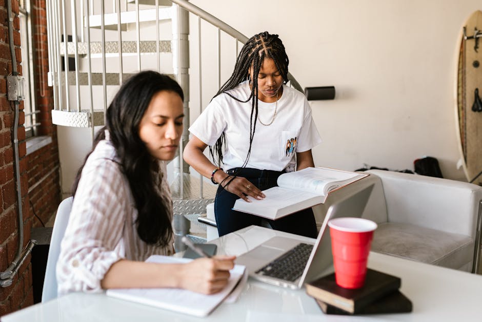College students studying together, using a laptop and books indoors.